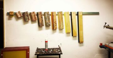 Siebdruckrakel von groß bis klein an der Werkstattwand.